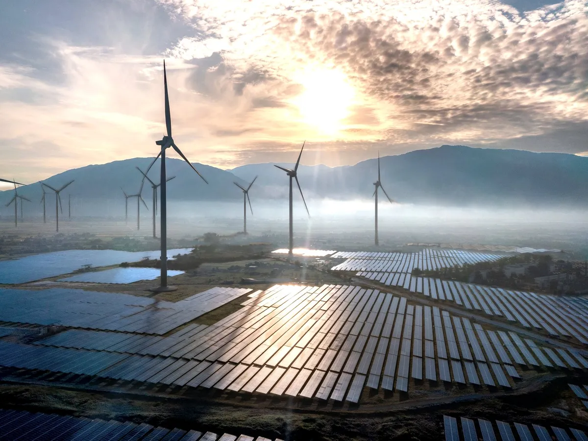Solar farm and wind turbines at sunrise